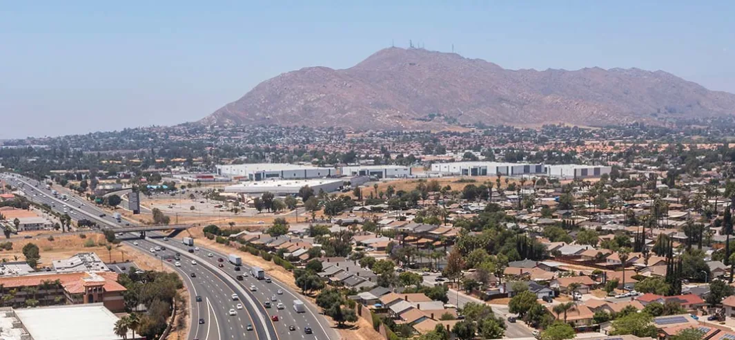 Aerial view of Moreno Valley, CA neighborhoods along the freeway with Box Springs Mountain behind