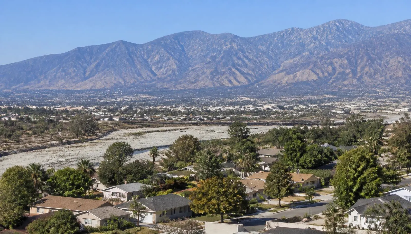 San Bernardino, CA neighborhood on the valley floor beside the dry Santa Ana River wash with the San Bernardino Mountains behind it